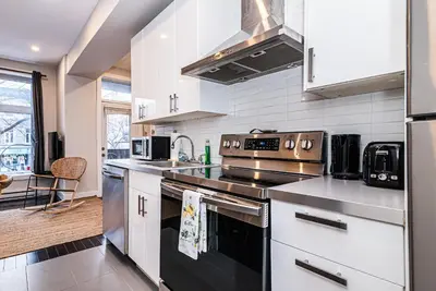 a kitchen with stainless steel appliances and white cabinets at Appartement Sur la 