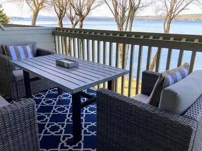 a table and chairs on a balcony with a view of the water at OMagogcondo com A in Magog-Orford