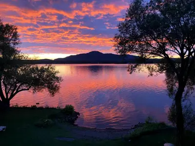 a sunset over a body of water with trees at OMagogcondo com B in Magog-Orford