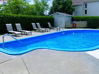 a large blue pool with chairs in a yard at OMagogcondo com B in Magog-Orford