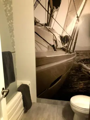 a bathroom with a toilet and a boat on the wall at OMagogcondo com B in Magog-Orford