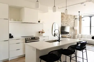 a kitchen with white cabinets and a kitchen island with black chairs at Maison Place Jacques-Cartier by Luxury In Transit in Montréal