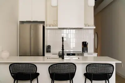 a kitchen with a counter with chairs and a refrigerator at Maison Place Jacques-Cartier by Luxury In Transit in Montréal