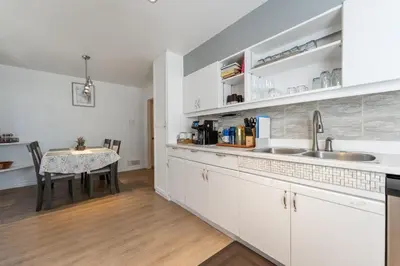 a kitchen with white cabinets and a dining table at Cozy Family Home Near Montreal in Brossard