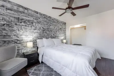 a bedroom with a white bed and a brick wall at Cozy Family Home Near Montreal in Brossard