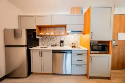 a kitchen with white cabinets and a stainless steel refrigerator at Candlewood Suites Trois-Rivières Ouest by IHG in Trois-Rivières