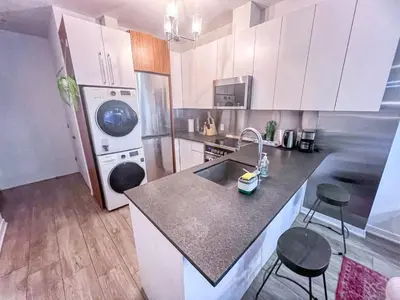 a kitchen with a sink and a counter with two stools at The Downtown Zando in Montréal