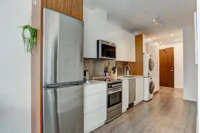 a kitchen with white cabinets and a stainless steel refrigerator at The Downtown Zando in Montréal