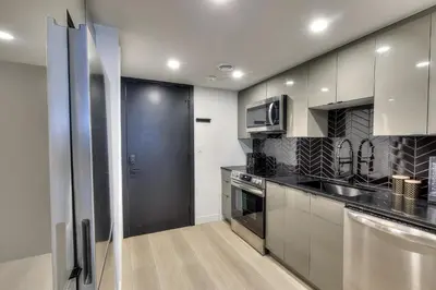 a kitchen with stainless steel appliances and a black refrigerator at Le Montreal Adventure! Restful Nights Full Kitchen & Fast Wifi in Montréal