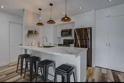 a kitchen with a large counter with stools in it at Condo-piscine à 200M du Memphré in Magog-Orford