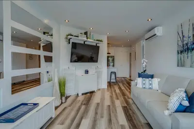 a living room with a white couch and a tv at Condo-piscine à 200M du Memphré in Magog-Orford