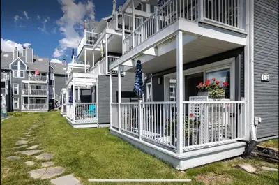a house with a balcony and an umbrella on a yard at Condo-piscine à 200M du Memphré in Magog-Orford