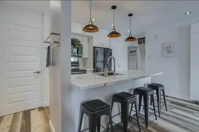 a kitchen with a counter with stools and a sink at Condo-piscine à 200M du Memphré in Magog-Orford