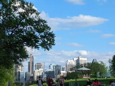 a group of people walking in a park with a city skyline at 2 Bedrooms, 1 Sofa bed and 1,5 Bathrooms, Renovated Apartment in the Heart of Plateau Mont-Royal in Montréal