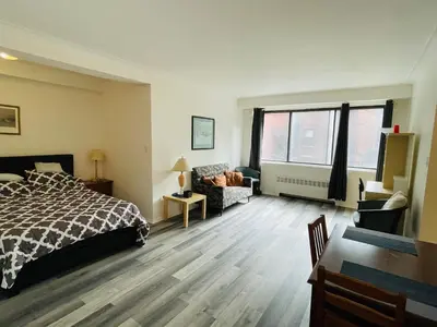 a bedroom with a bed and a couch and window at Stylish Montreal Apartment in Montréal