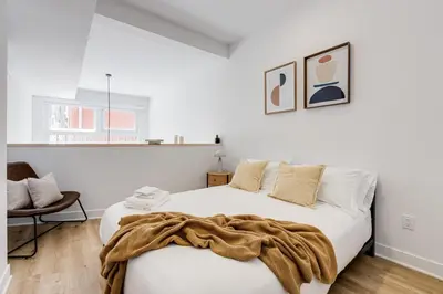 a white bedroom with a bed with a blanket on it at Le Mile End by M11 - Modern Luxe 1BDR with Sofa Bed in Montréal