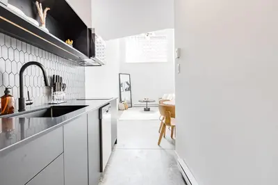 a kitchen with white cabinets and a sink at Le Mile End by M11 - Modern Luxe 1BDR with Sofa Bed in Montréal