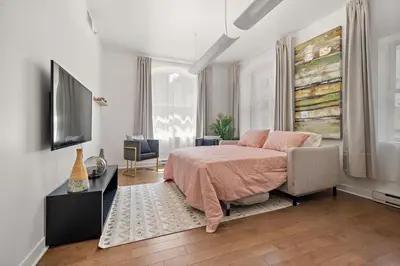 a bedroom with a bed and a flat screen tv at Old Montreal's Luxe Charm in Montréal