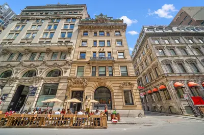a group of people sitting at tables in front of a building at Old Montreal's Luxe Charm in Montréal