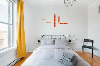 a white bedroom with a bed and a window at Frontenac residences in Montréal