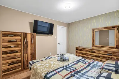 a bedroom with a bed and a tv on the wall at 2 BDR -10 min de la Ronde et Parc Jean Drapeau South Shore Montreal in Longueuil