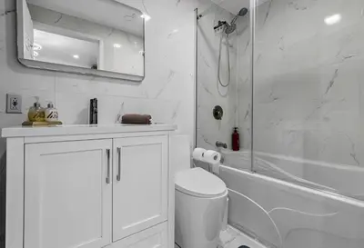 a white bathroom with a shower and a toilet at 2 BDR -10 min de la Ronde et Parc Jean Drapeau South Shore Montreal in Longueuil