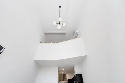 a room with white walls and a ceiling with a chandelier at Le Mile End by M11 - Luxurious Two-Floor 1BDR Loft in Montréal