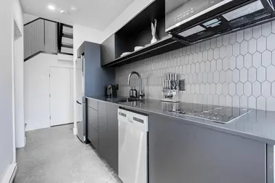 a black and white kitchen with a sink and a dishwasher at Le Mile End by M11 - Luxurious Two-Floor 1BDR Loft in Montréal