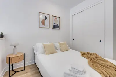 a white bedroom with a white bed and a table at Le Mile End by M11 - Modern & Stylish 1BDR with Sofa Bed in Montréal