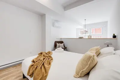 two beds in a bedroom with white walls at Le Mile End by M11 - Modern & Stylish 1BDR with Sofa Bed in Montréal