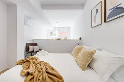 a white bedroom with a bed and a chair at Le Mile End by M11 - Modern & Stylish 1BDR with Sofa Bed in Montréal