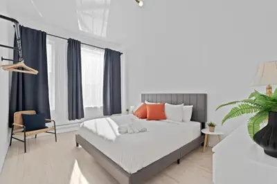 a bedroom with a large bed and a chair at New Modern 2bdr Apartment in Little Italy in Montréal