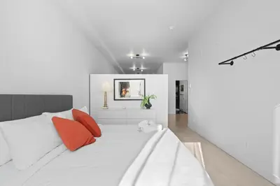 a white bedroom with a bed with red pillows at New Modern 2bdr Apartment in Little Italy in Montréal
