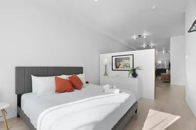 a white bedroom with a large bed with orange pillows at New Modern 2bdr Apartment in Little Italy in Montréal
