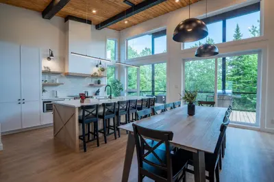 an open kitchen with a large wooden table and chairs at Évasion Nature Adstock - Sauna, Ski & Spa in Thetford Mines