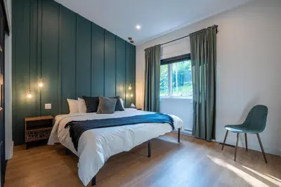 a bedroom with a large bed and a green wall at Évasion Nature Adstock - Sauna, Ski & Spa in Thetford Mines