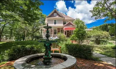 a house with a fountain in front of a house at Ô Café Crème in Magog-Orford