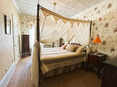 a bedroom with a canopy bed in a room with wallpaper at Ô Café Crème in Magog-Orford