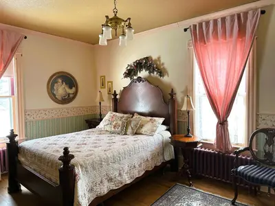 a bedroom with a large bed with pink curtains at Ô Café Crème in Magog-Orford