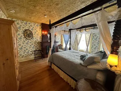 a bedroom with a canopy bed and blue and white wallpaper at Ô Café Crème in Magog-Orford