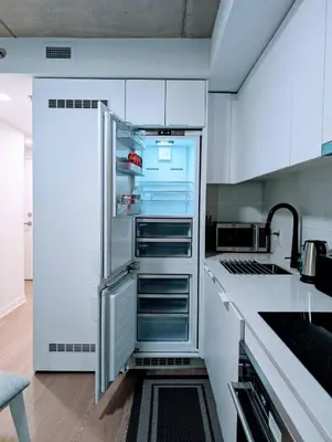 an empty refrigerator in a kitchen with white cabinets at Cozy Studio in Montreal's Quartier des Spectacles in Montréal