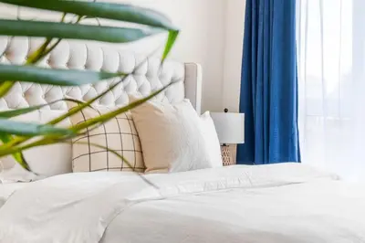 a bedroom with a white bed with a blue curtain at Central King Studio in Montréal