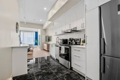 a kitchen with white cabinets and a black tile floor at Central King Studio in Montréal