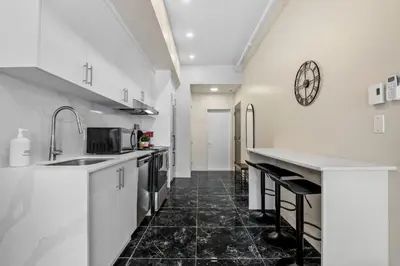 a kitchen with white cabinets and a clock on the wall at Central King Studio in Montréal