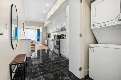 a kitchen with white cabinets and a black tile floor at Central King Studio in Montréal