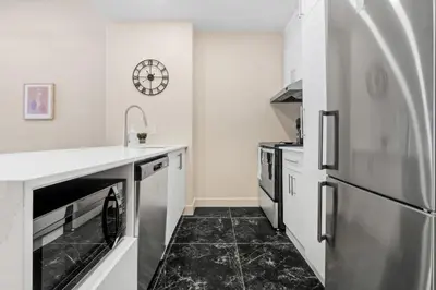 a kitchen with white appliances and a black tile floor at Central King Loft in Montréal