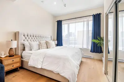 a white bedroom with a large bed with blue curtains at DownTown King Suite in Montréal
