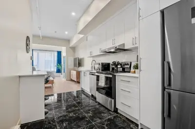 a kitchen with white cabinets and a black tile floor at DownTown King Suite in Montréal