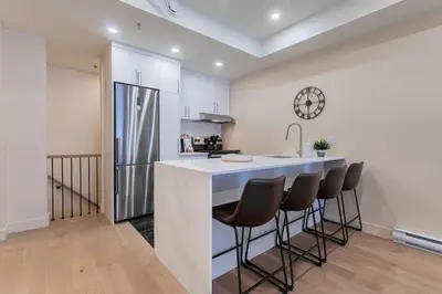 a kitchen with a counter with chairs and a sink at Double King Luxury 2BR Condo in Montréal