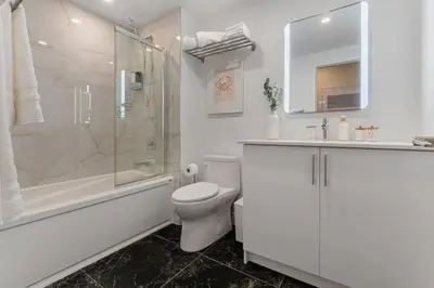 a white bathroom with a toilet and a shower at Double King Luxury 2BR Condo in Montréal